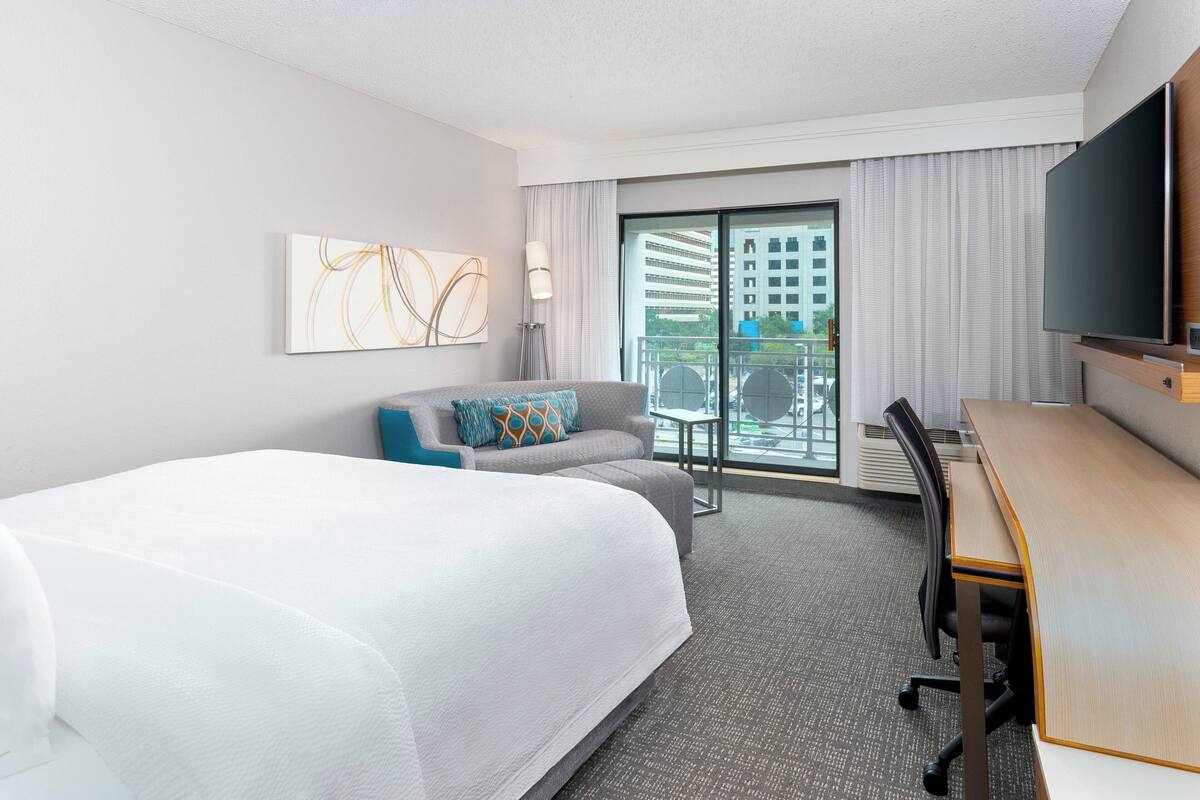 Une chambre d’hôtel avec un grand lit, un bureau, un canapé et une télévision.