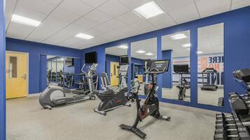 A gym with exercise equipment, mirrors, and a blue wall.