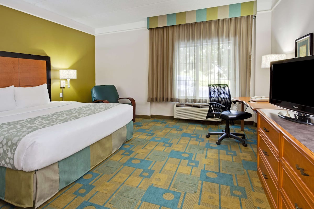 A hotel room with a large bed, a desk with a computer, a chair, and a television.
