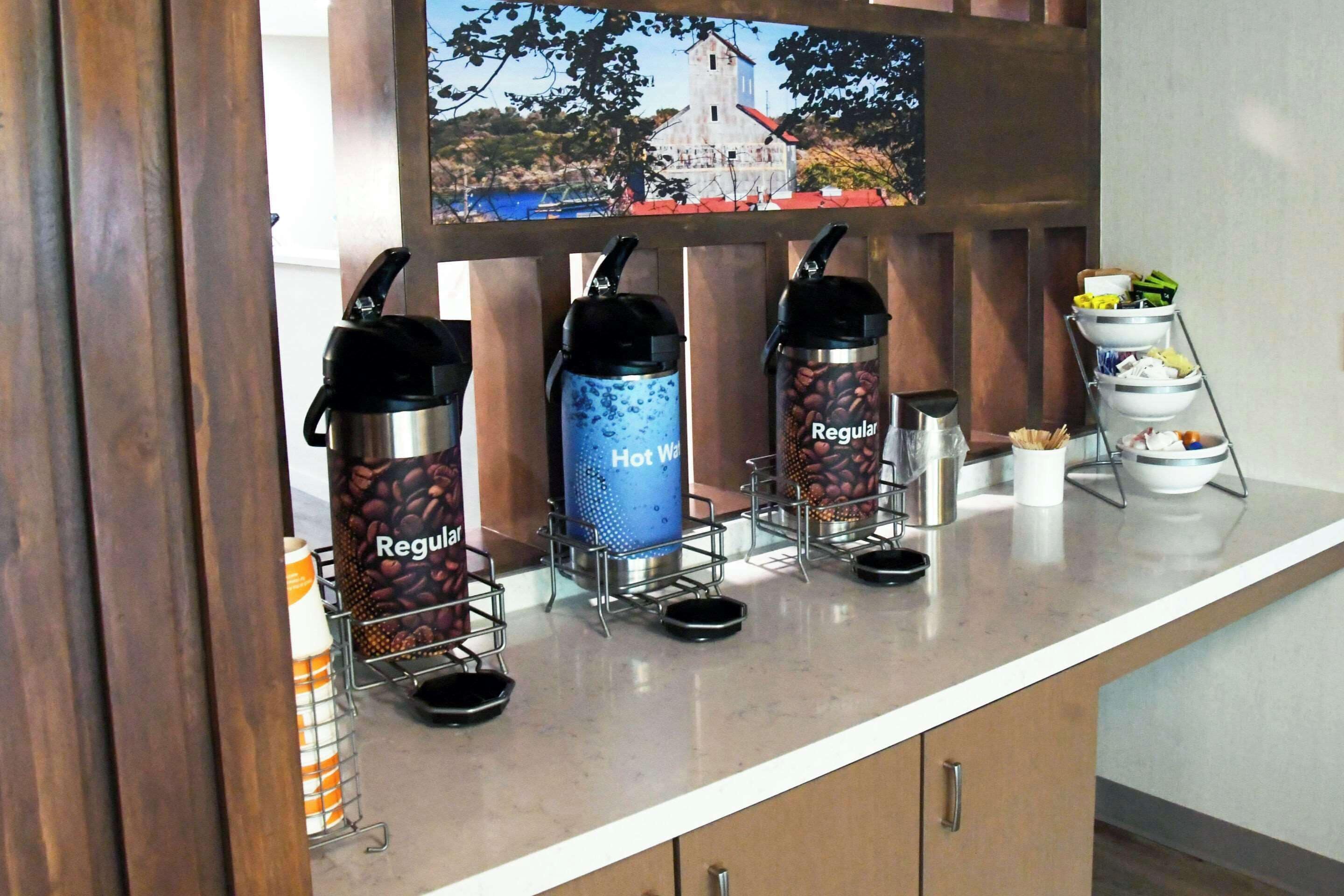 Un espace dédié au café, équipé de trois distributeurs de café étiquetés « Café normal », « Eau chaude » et « Café normal ».
