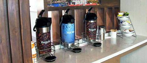 Una estación de café con tres dispensadores de café etiquetados como