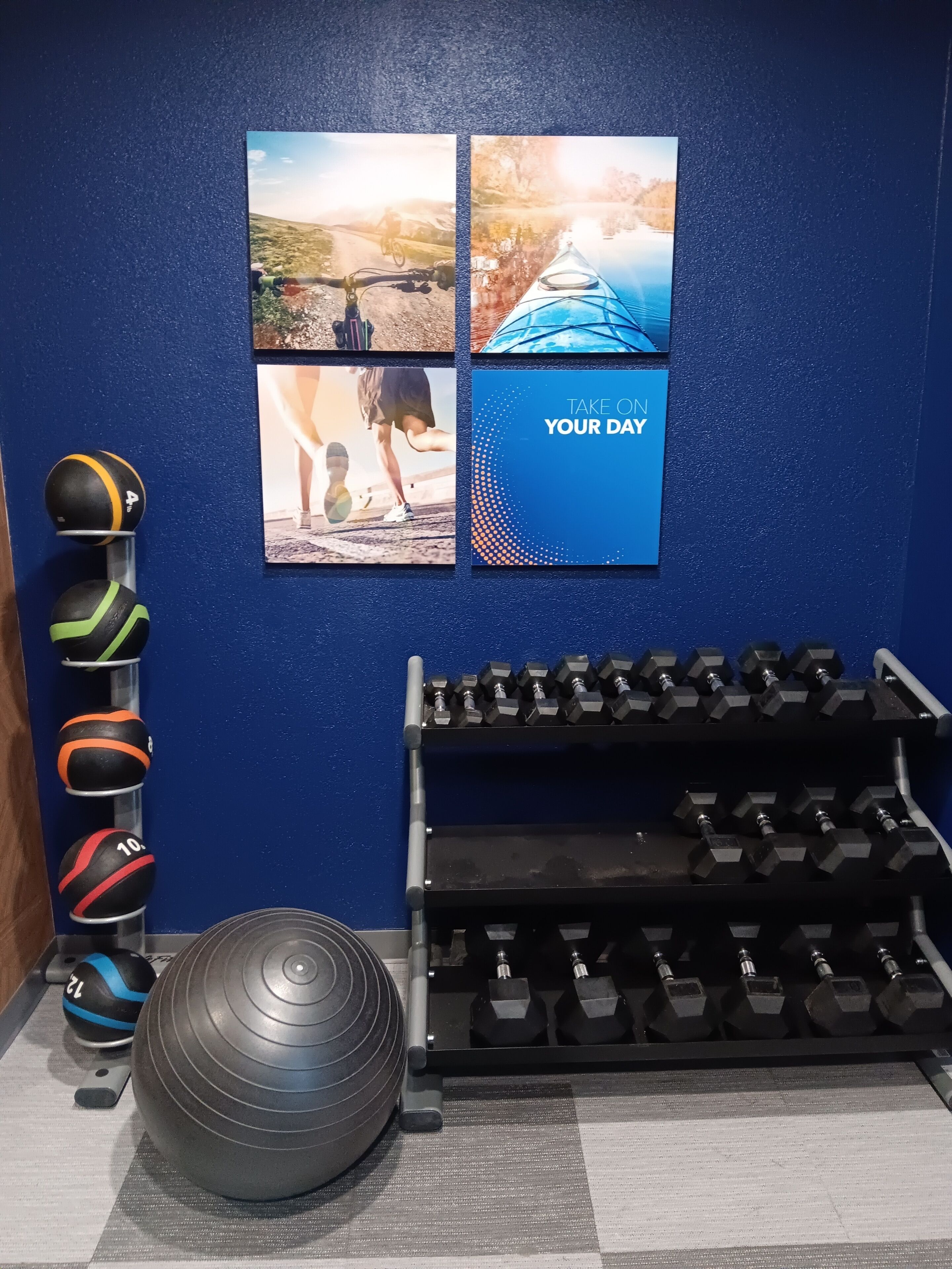 A gym with exercise equipment, including medicine balls, a kettlebell, and dumbbells.