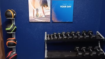 A gym with exercise equipment, including medicine balls, a kettlebell, and dumbbells.