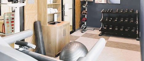 Un gimnasio con equipo de ejercicio, un zapatero y un cartel en la pared.