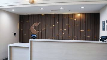 A reception desk with a modern design, featuring a wooden panel wall and a large crescent moon logo.