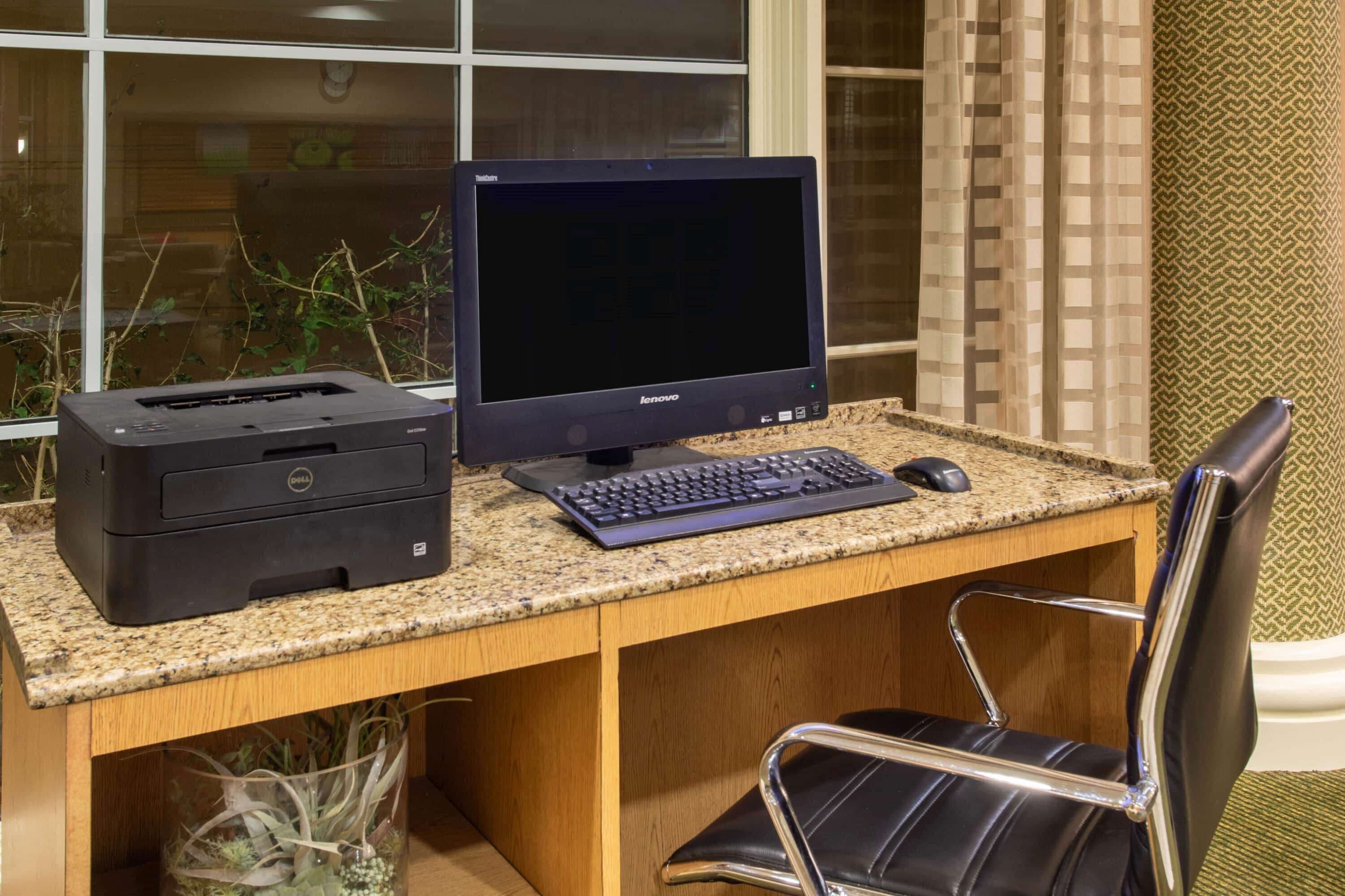 A wooden desk with a desktop computer, keyboard, and mouse.