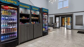 Eine Hotelhalle mit drei Getränkeautomaten, beschriftet mit „HYDRATE“, „RECHARGE“ und „NOURISH“.