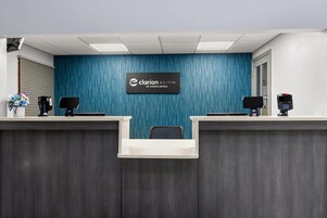 Una mesa de recepción con una pared azul texturizada, un logotipo de 'clarion pointe by choice hotels' y dos lectores de tarjetas.