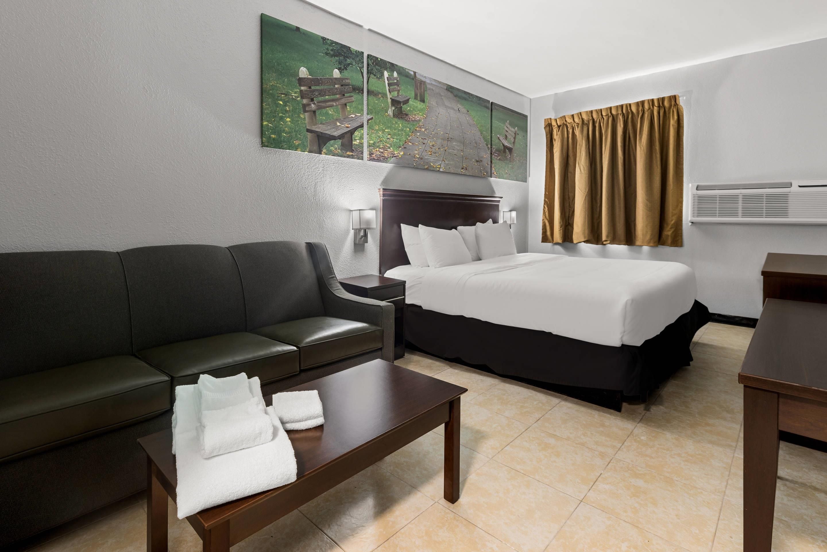 Een hotelkamer met een bed, een bank, een bijzettafeltje en een schilderij aan de muur.