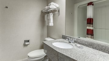 A modern bathroom with a granite countertop, a white toilet, and a glass shower enclosure.