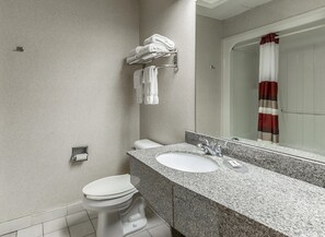 Un baño moderno con encimera de granito, inodoro blanco y cabina de ducha de vidrio.