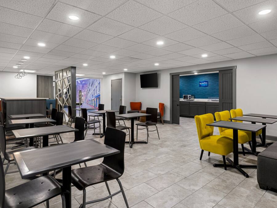 Un espace repas moderne, avec des tables et des chaises, un écran de télévision et un mur décoratif.