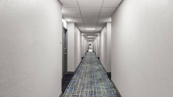 Un pasillo largo y estrecho con paredes blancas y una alfombra estampada.