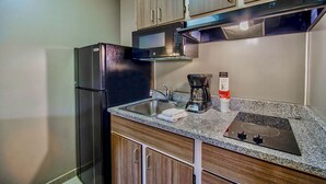 A compact kitchen with a refrigerator, microwave, stove, sink, and wooden cabinets. -  Studio 6 Deer Valley (Phoenix)