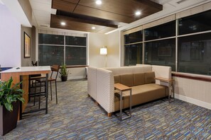 A modern interior with a sofa, a desk, chairs, and a patterned carpet. - Holiday Inn Express Hotel & Suites Downtown Minneapolis by IHG (Minneapolis)