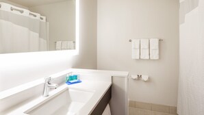 A modern bathroom with a white sink, a mirror, and a shower curtain. - Holiday Inn Express Hotel & Suites Downtown Minneapolis by IHG (Minneapolis)