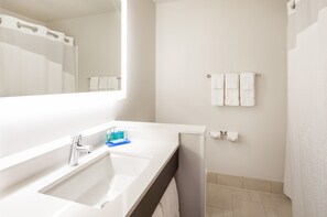 Une salle de bain moderne avec un lavabo blanc, un miroir et un rideau de douche.