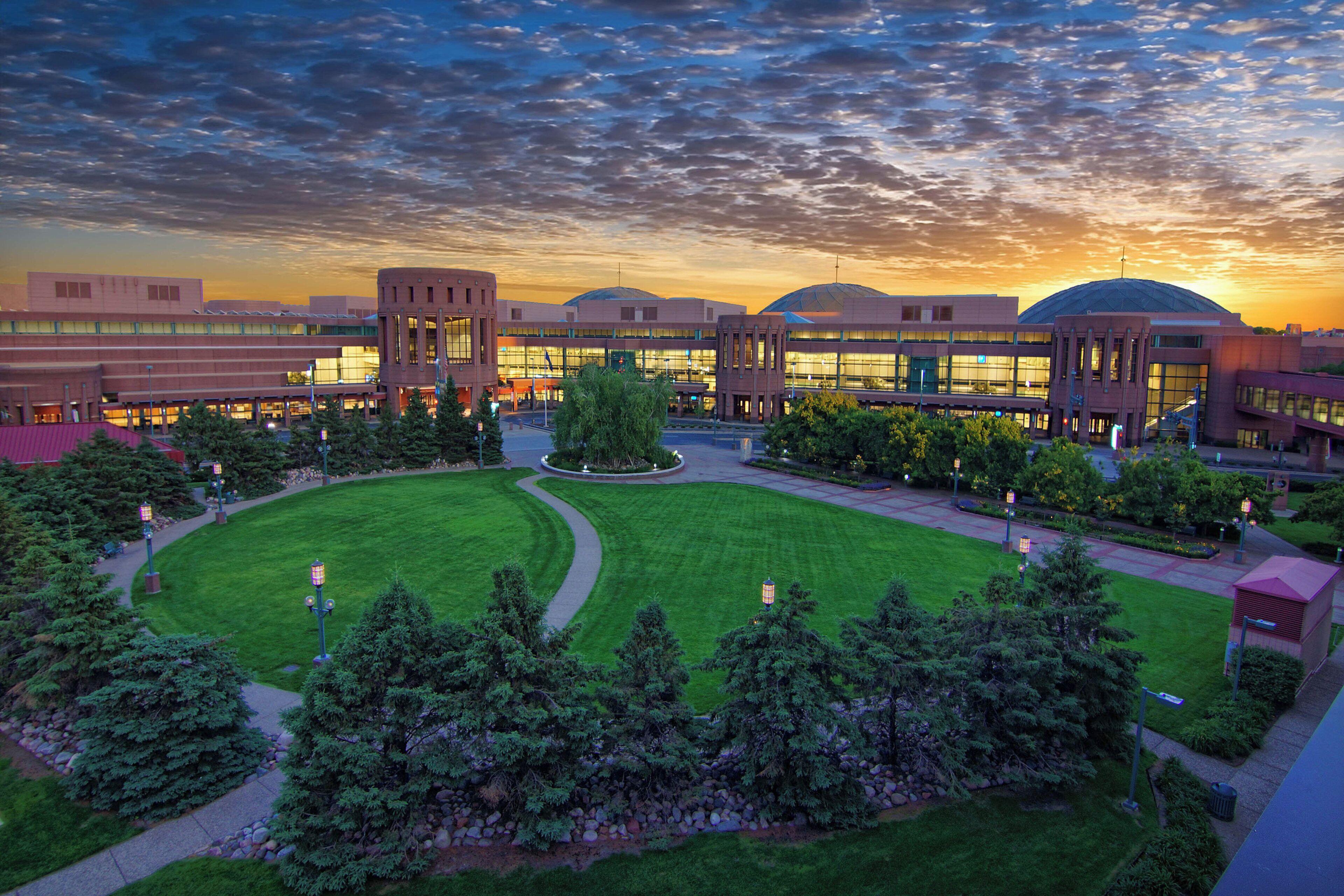 A large building complex with multiple structures, a central circular lawn, and surrounding greenery.