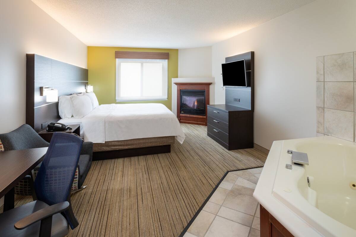 Une chambre d’hôtel équipée d’un lit, d’un bureau, d’une chaise, d’une télévision et d’une baignoire.