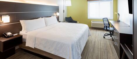 A hotel room with a large bed, bedside tables, a desk with a chair, a flat-screen TV, and a window with a view.
