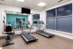 A fitness room with treadmills, a weight bench, and a mirror.