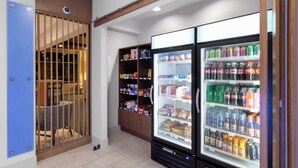 Une chambre d’hôtel équipée d’un minibar, d’un coin salon avec un fauteuil et d’un réfrigérateur rempli de boissons.