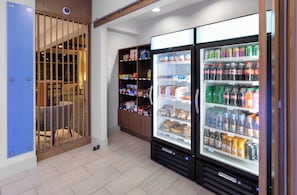 A hotel room with a minibar, a seating area with a chair, and a refrigerator stocked with beverages.