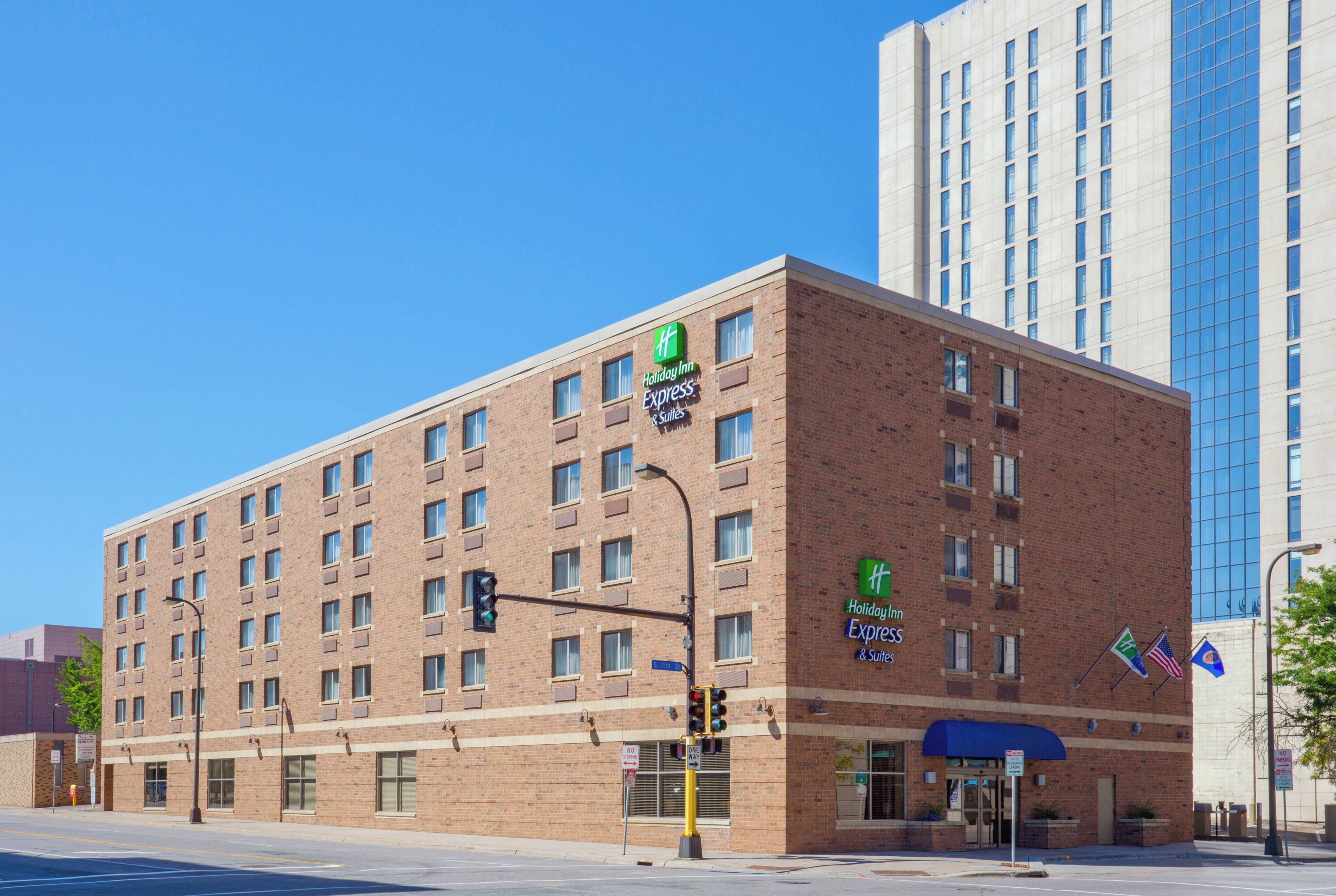 A Holiday Inn Express & Suites hotel with a brick facade, multiple windows, and a blue awning at the entrance.