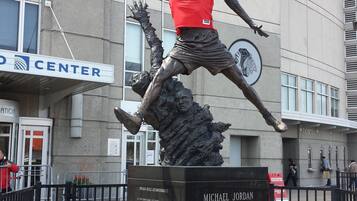 Una estatua de baloncesto de Michael Jordan con camiseta roja y el número 23, ubicada frente a un edificio con un letrero que dice 'CENTER'.