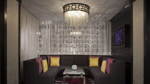 Una sala de estar moderna con un sofá oscuro, una mesa de centro de vidrio y una lámpara de araña decorativa.