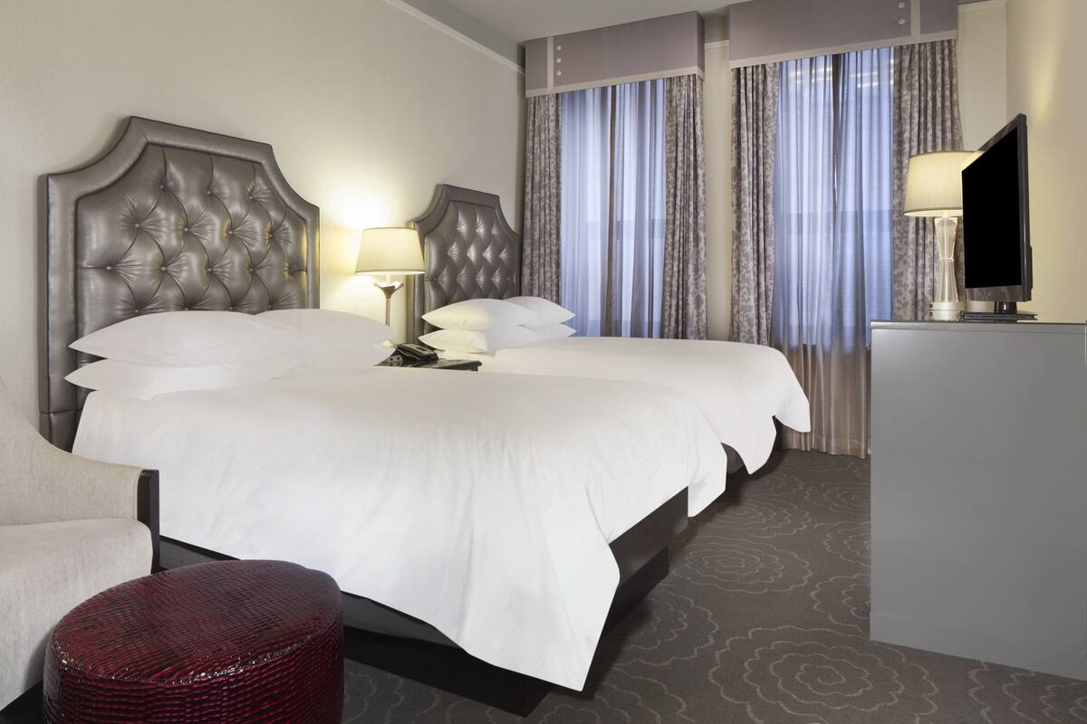 A hotel room with a large bed, a TV, a desk, and a chair.