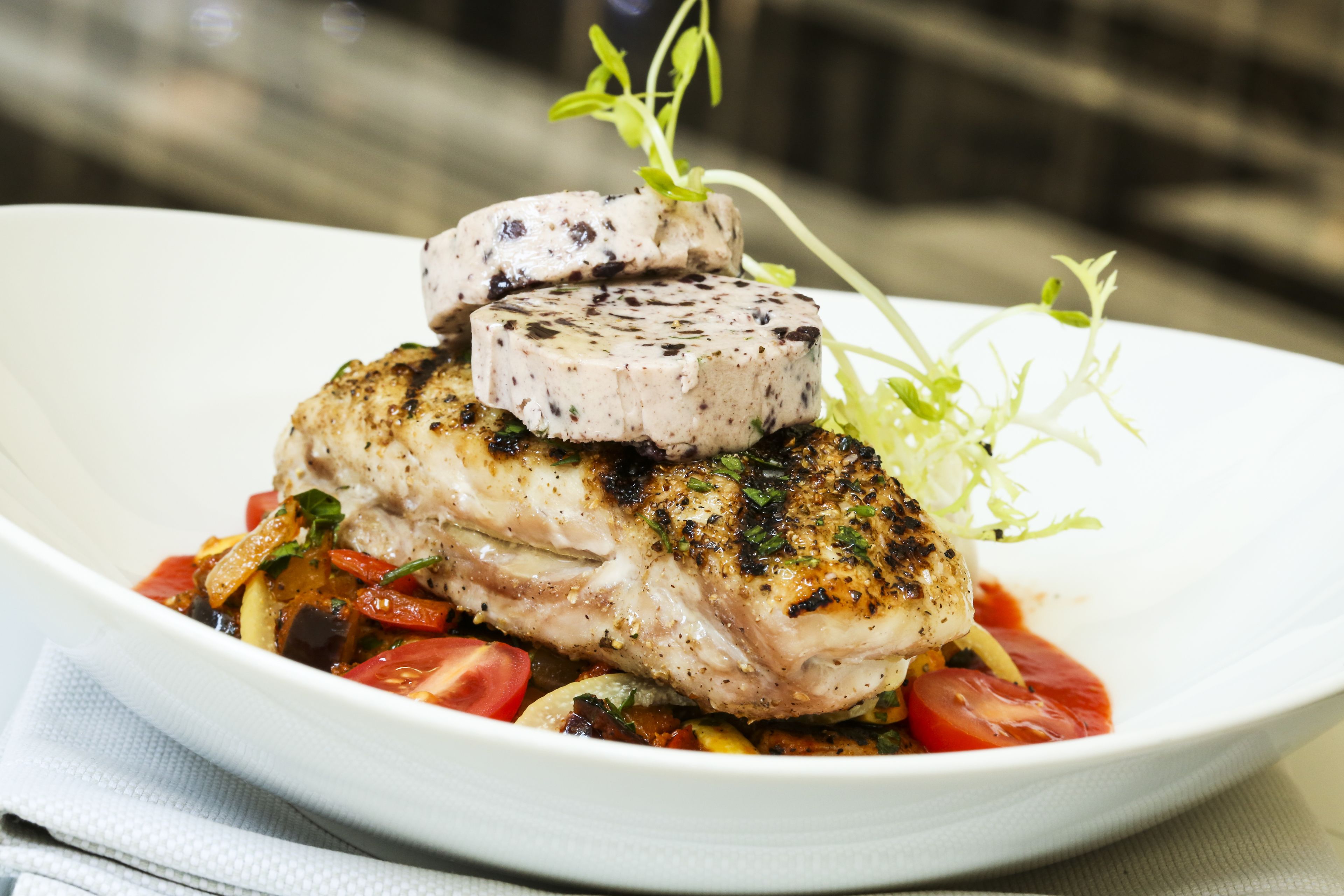 Un plato de comida con un trozo de pescado, carne y verduras.