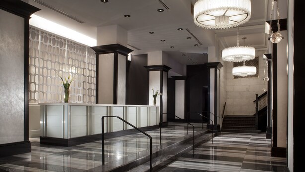 A modern hotel lobby with a reception desk, marble flooring, and elegant chandeliers. - Silversmith Hotel Chicago Downtown (Chicago)