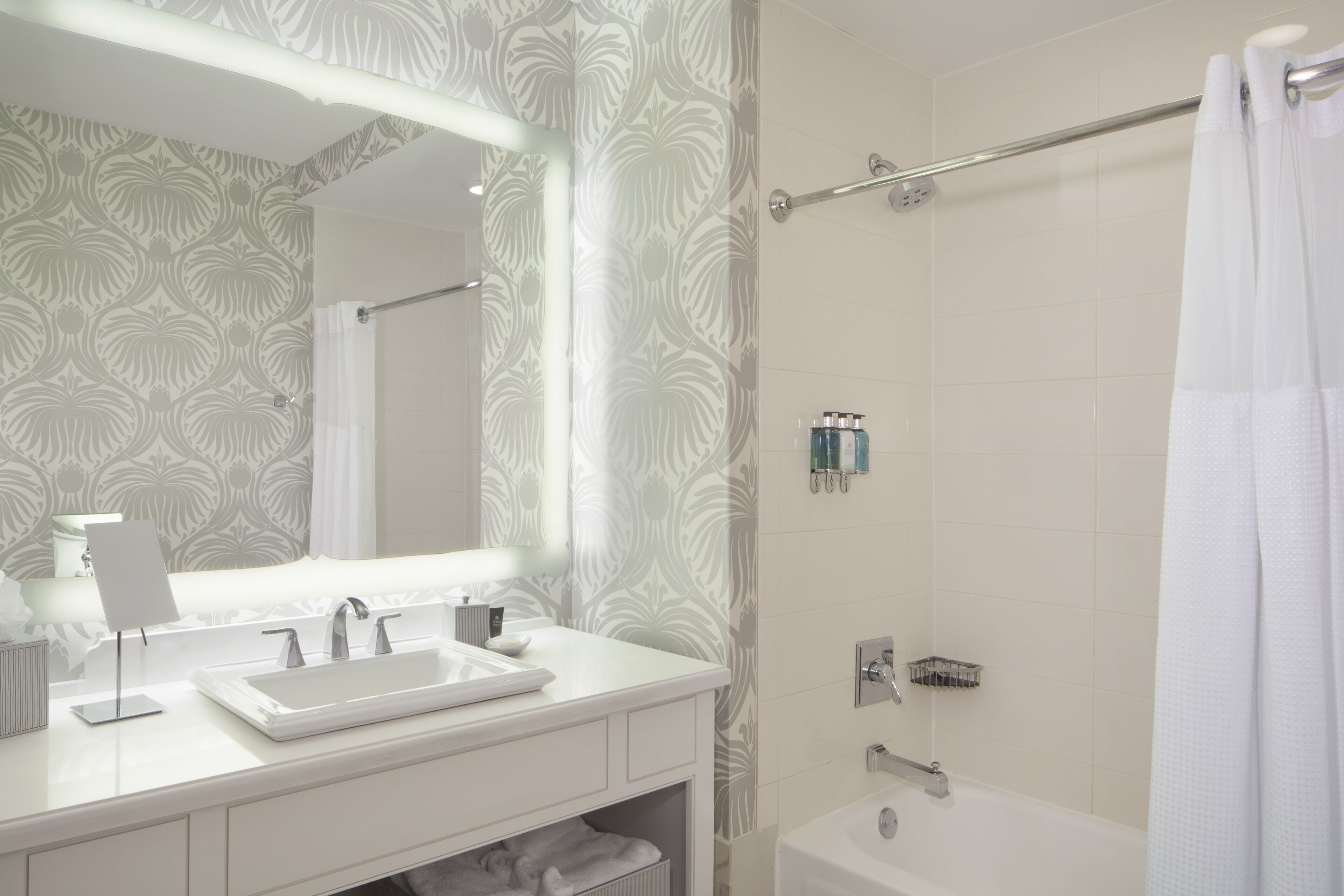 A modern bathroom with a white sink, mirror, and shower.