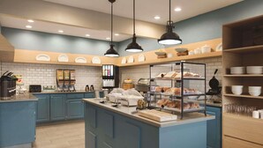 A modern kitchen with blue cabinets, a central island with a glass display case, and overhead pendant lighting. - Country Inn & Suites by Radisson, Indianapolis South, IN (Indianapolis)