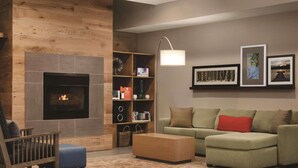 A living room with a fireplace, a sofa, a coffee table, and a bookshelf. - Country Inn & Suites by Radisson, Indianapolis South, IN (Indianapolis)