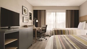A hotel room with a bed, a desk with a computer, a chair, a TV, and framed pictures on the wall. - Country Inn & Suites by Radisson, Indianapolis South, IN (Indianapolis)