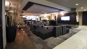 A modern lobby with a Christmas tree, seating area, and a TV screen. - Courtyard by Marriott Indianapolis South (Indianapolis)