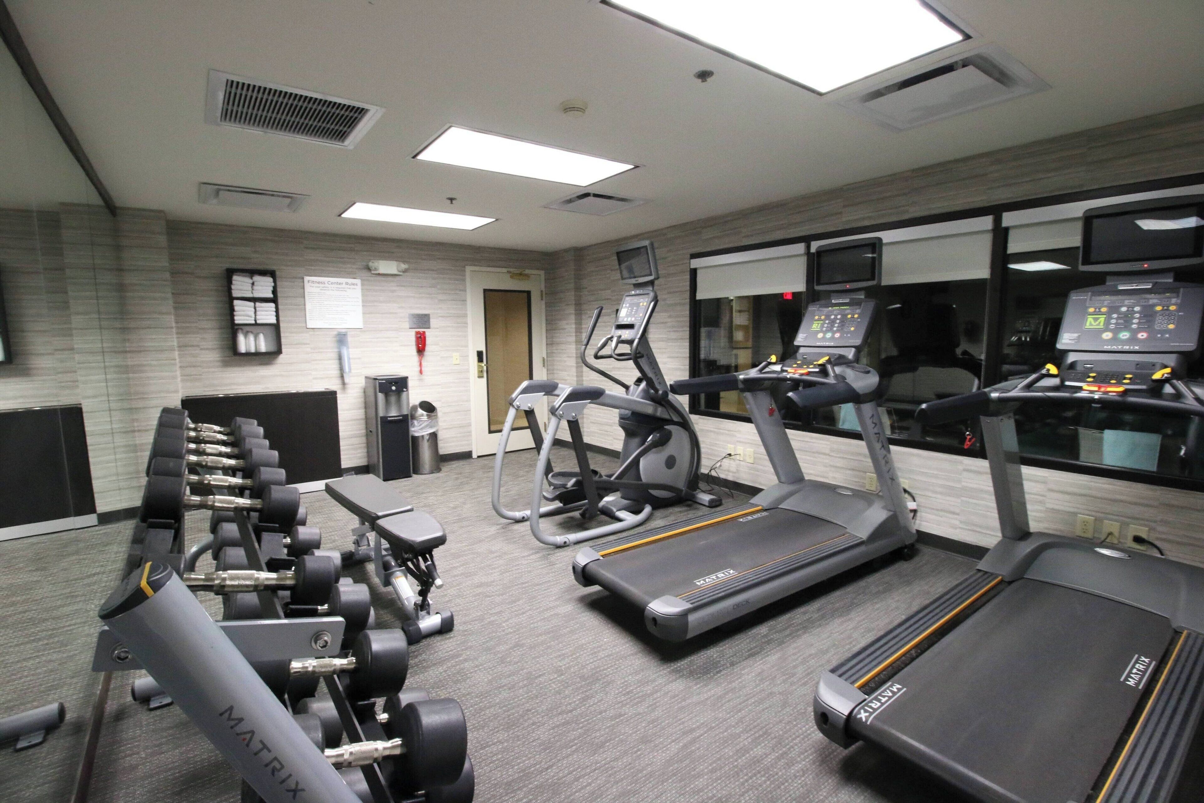 A gym with treadmills, elliptical machines, and weight benches.