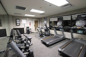 A gym with treadmills, elliptical machines, and weight benches. - Courtyard by Marriott Indianapolis South (Indianapolis)