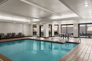 A swimming pool with a tiled deck, chairs, and tables for relaxation. - Courtyard by Marriott Indianapolis South (Indianapolis)