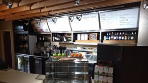 A breakfast bar with a menu board above, a refrigerated display case, and a beverage dispenser. - Courtyard by Marriott Indianapolis South (Indianapolis)