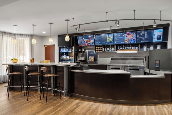 A modern bar area with a counter, stools, and a menu display.