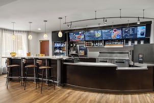 Un'area bar moderna con un bancone, sgabelli e una vetrina per il menu.