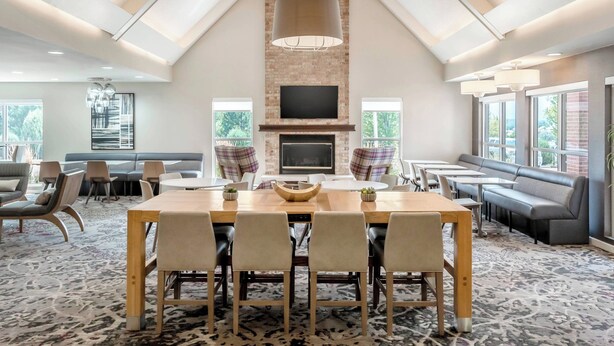 A spacious room with a high ceiling, a fireplace, a large dining table, and comfortable seating areas. - Residence Inn by Marriott Denver North-Westminster (Westminster)