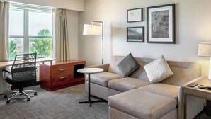 A hotel room with a sofa, a desk, a chair, a lamp, and framed pictures on the wall. - Residence Inn by Marriott Denver North-Westminster (Westminster)