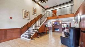 A spacious lobby with a wooden staircase, a reception desk, and a seating area. - Quality Inn & Suites Dawsonville (Dawsonville)