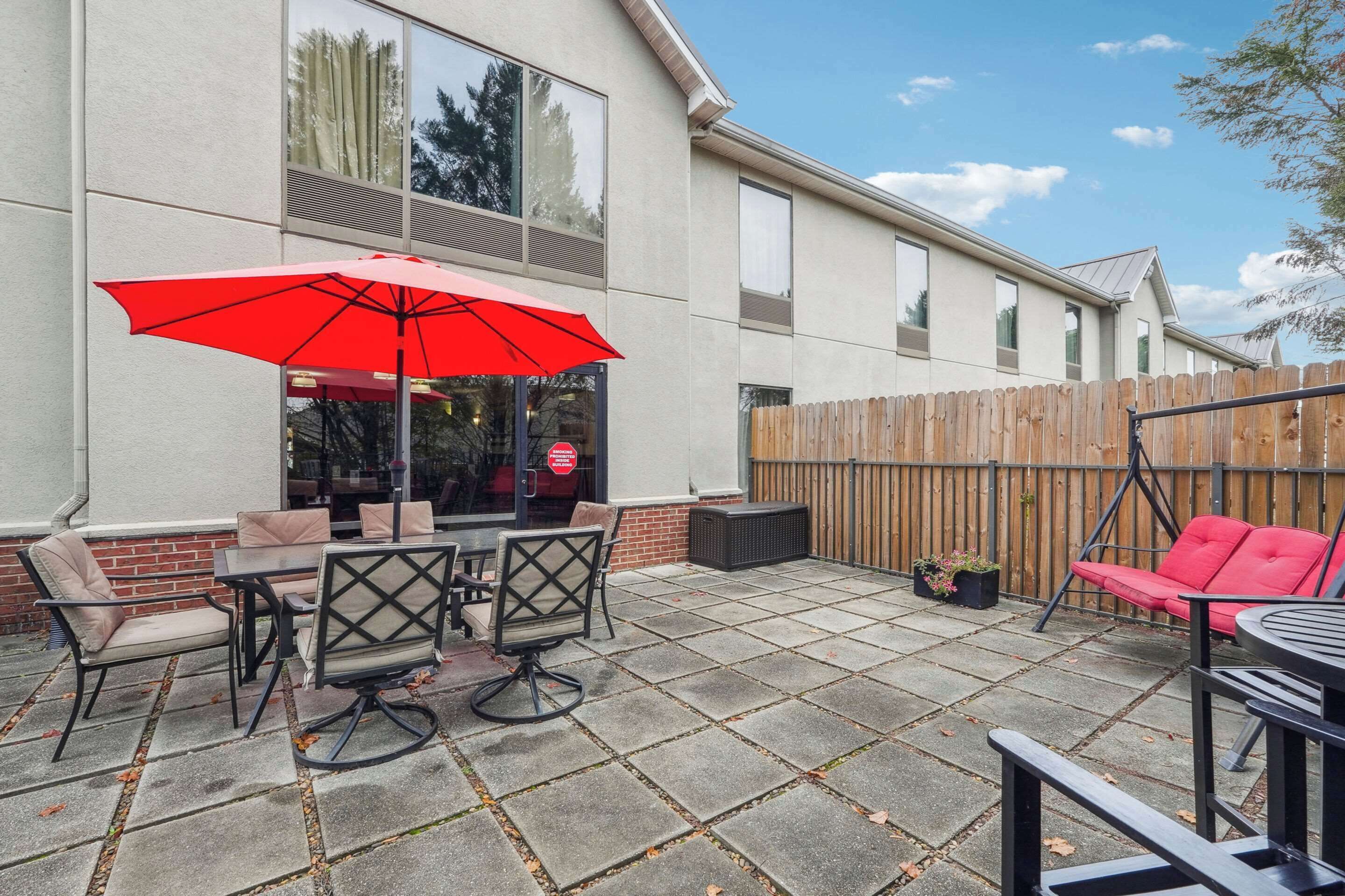 A patio with a red umbrella, outdoor furniture, and a wooden fence.