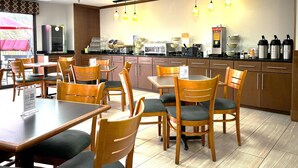 A restaurant with wooden tables and chairs, a counter with a coffee machine, and a view of the outside. - Quality Inn & Suites Dawsonville (Dawsonville)