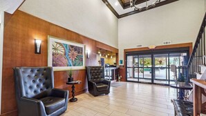A spacious lobby with two leather armchairs, a large painting, and a staircase leading to an upper level. - Quality Inn & Suites Dawsonville (Dawsonville)